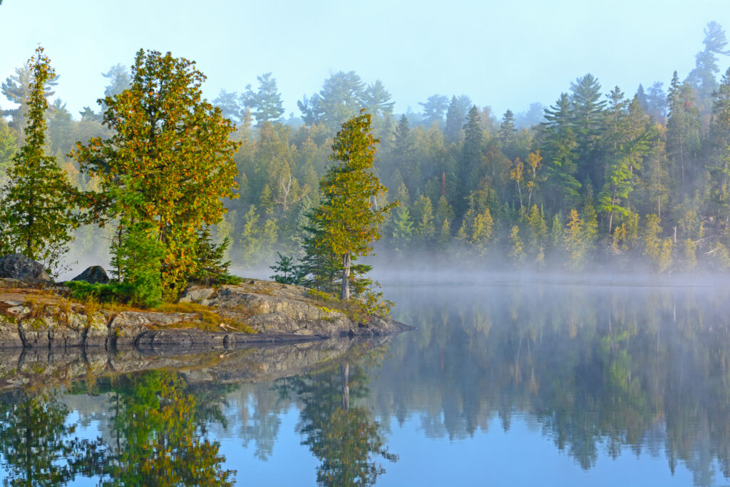 Canoe navigating through the pristine waters of the Boundary Waters Canoe Area in Minnesota, surrounded by dense forests.